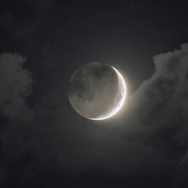 Shimmering Crescent Among Clouds
